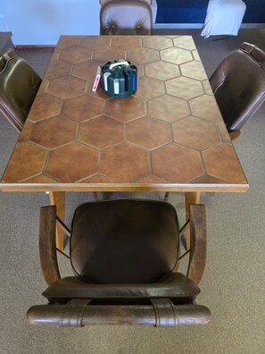 A hexagonal-tiled table with a black object on it, surrounded by leather chairs. - Peaceful Lakefront Retreat | 5* View, Dock, Games (Eatonton)