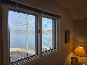 A room with two windows, a lamp, and a framed picture on the wall. - Peaceful Lakefront Retreat | 5* View, Dock, Games (Eatonton)