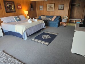 A bedroom with a bed, a sofa, a desk, and a rug. - Peaceful Lakefront Retreat | 5* View, Dock, Games (Eatonton)