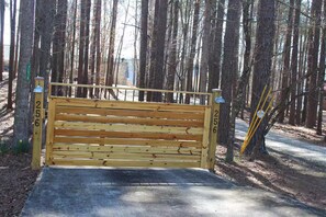 A wooden bench with a metal railing, surrounded by trees. - Peaceful Lakefront Retreat | 5* View, Dock, Games (Eatonton)