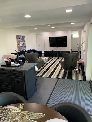 A modern living room with a flat-screen TV, a sofa, a coffee table, and a striped rug.