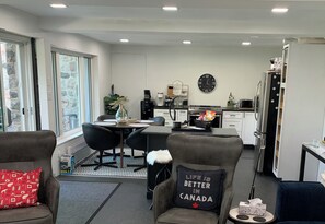 A modern kitchen with a dining area, featuring a coffee machine, a clock, and a refrigerator.