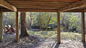 Un pavelló de fusta amb vista a una zona boscosa i una taula de picnic amb caires.