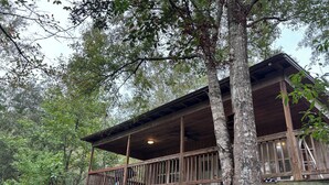 Una cabana de fusta amb un balcó, envoltada d'arbres.