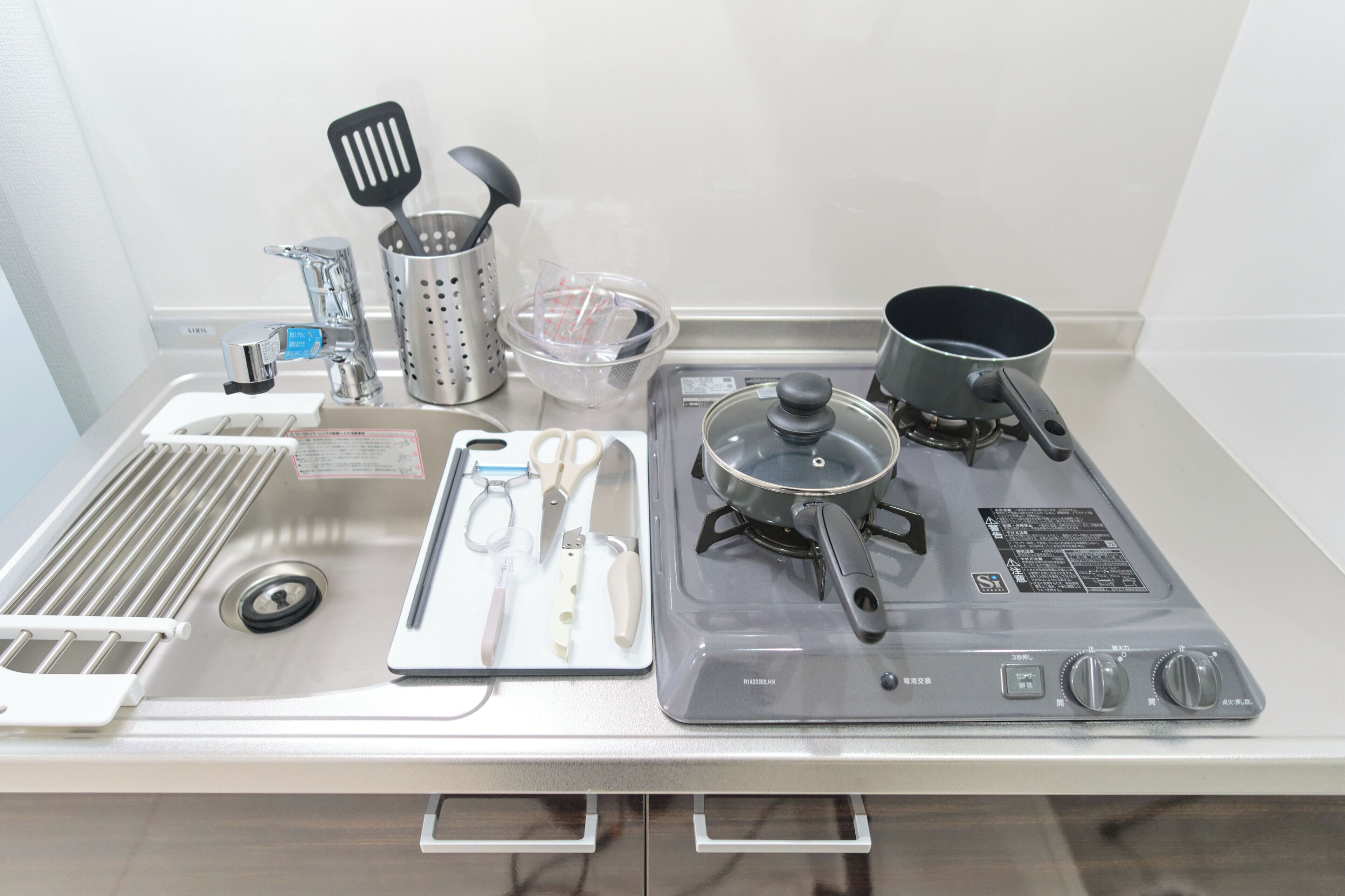 A kitchen with a stove, pots, a colander, and various utensils.