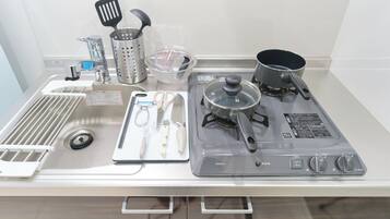 A kitchen with a stove, pots, a colander, and various utensils.