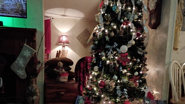 Un árbol de Navidad con luces y adornos, rodeado de regalos envueltos.