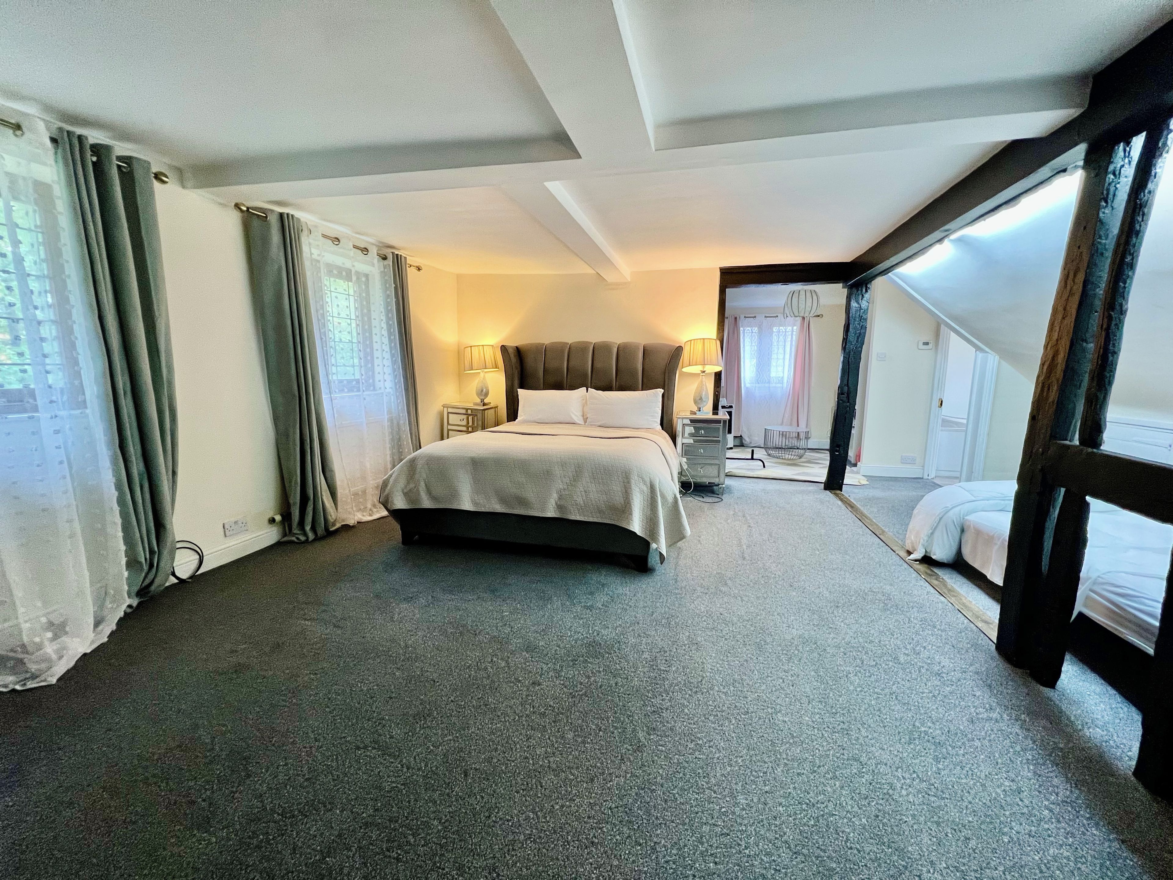 Une chambre d’hôtel avec un grand lit, une table de chevet, une lampe et une vue sur l’extérieur.