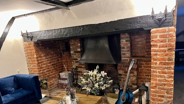 Una habitación acogedora con chimenea de ladrillo, sofás azules, una mesa de centro de madera y una guitarra.