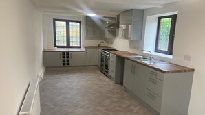 Una cocina con suelo de espiga, horno empotrado, estufa y ventana con vistas.