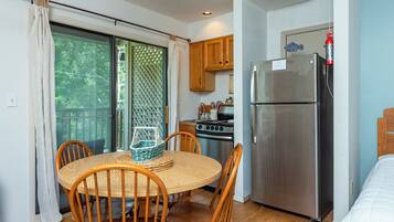 A compact kitchen with a refrigerator, stove, and wooden cabinets.