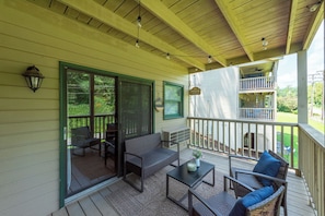 Eine überdachte Veranda mit Gartenmöbeln, einem Deckenventilator und Blick auf den Garten.