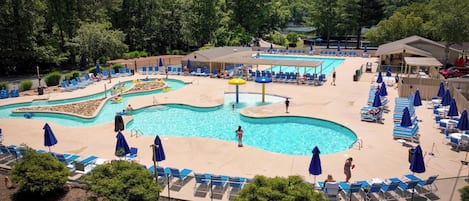 A pool area with multiple swimming pools, lounge chairs, and umbrellas.
