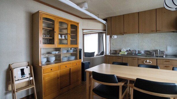 Una cocina compacta con armarios de madera, una mesa de comedor con sillas y una ventana con cortinas.