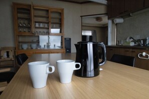 A wooden dining table with two white mugs and a black coffee pot. - Niseko Homey Home (Kutchan-cho)