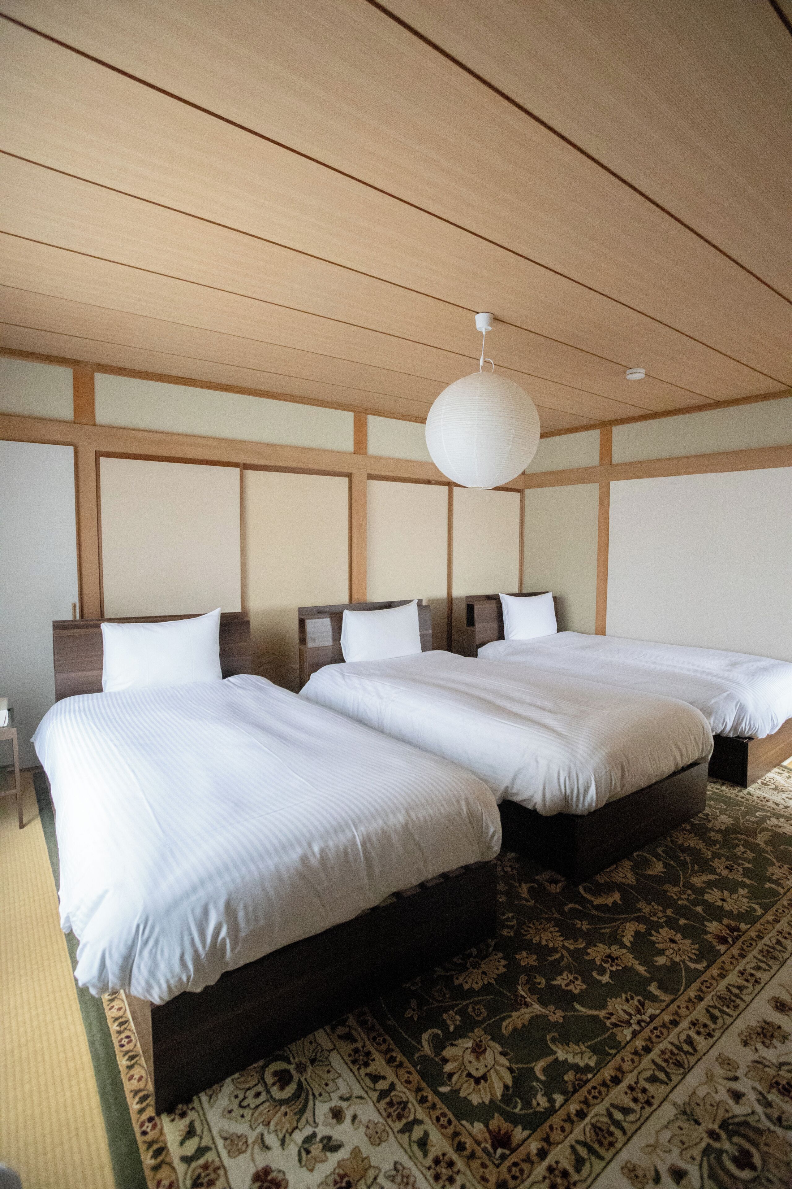 Ein Hotelzimmer mit zwei Betten, einer Holzzahlendecke und einer hängenden Leuchte.