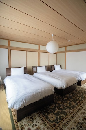 A hotel room with two beds, a wooden ceiling, and a hanging light fixture.