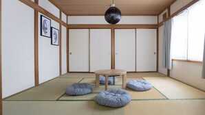 Una habitación japonesa tradicional con suelo de tatami, una mesa de madera y una lámpara colgante.
