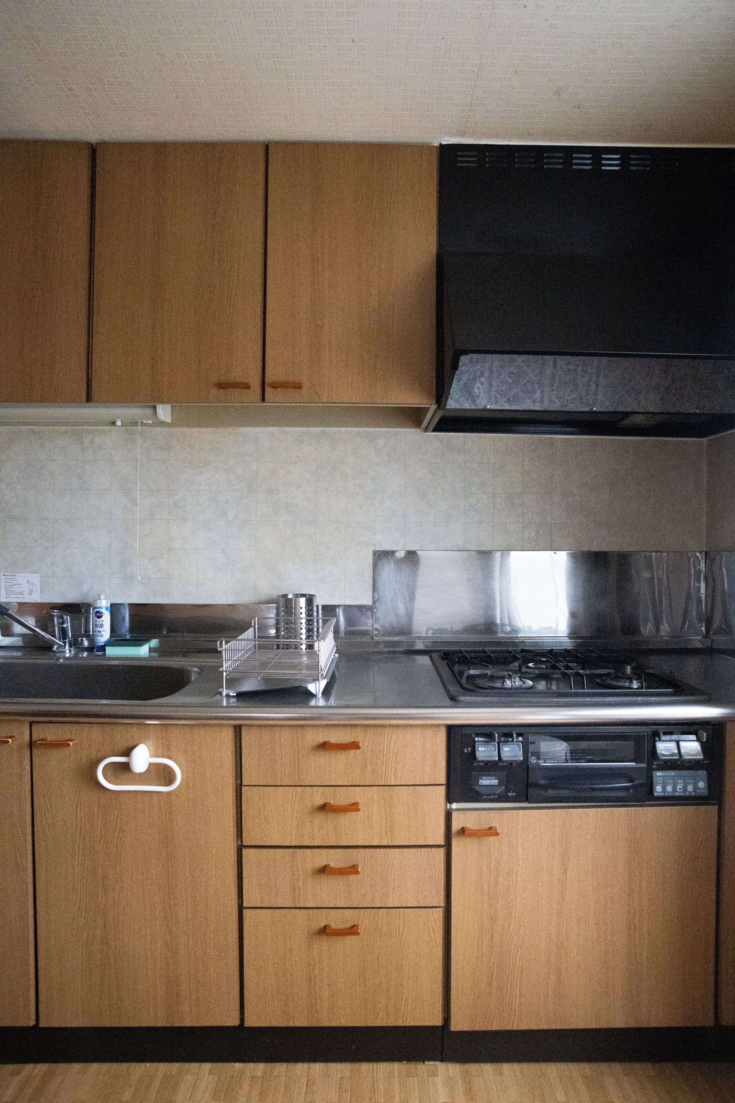 Una cocina con armarios de madera, un lavamanos de acero inoxidable, una estufa y un lavavajillas.