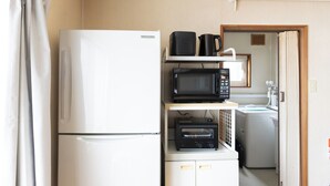 Una kitchenette compacta con refrigerador, microondas, tostadora y cafetera.