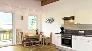 Una cocina moderna con armarios blancos, horno empotrado y cafetera.