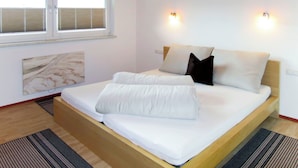 Un dormitorio con cama, dos luces empotradas en la pared, una ventana con persianas y una obra de arte de mármol en la pared.