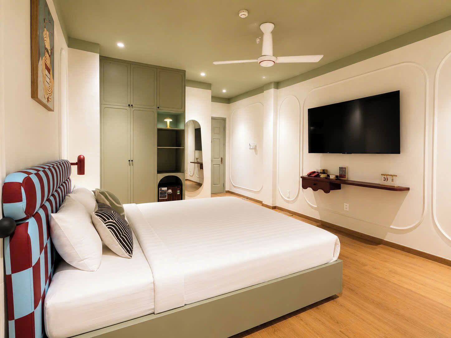 Une chambre à coucher avec un lit, une télévision, une armoire et un ventilateur de plafond.