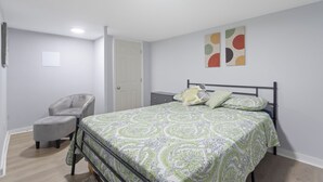 Ein Schlafzimmer mit einem Bett, einem Sessel, einem Nachttisch und einer Tür.