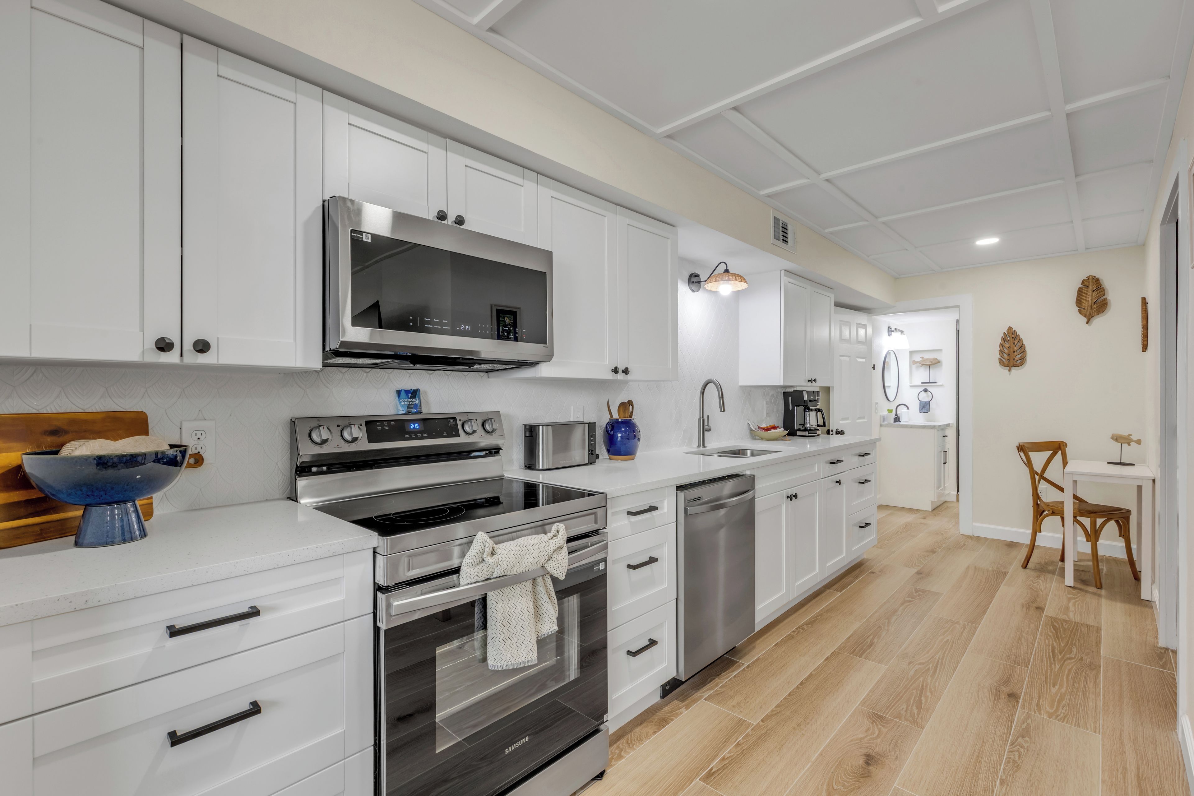 Una cocina moderna con armarios blancos, electrodomésticos de acero inoxidable y una mesa de comedor de madera.