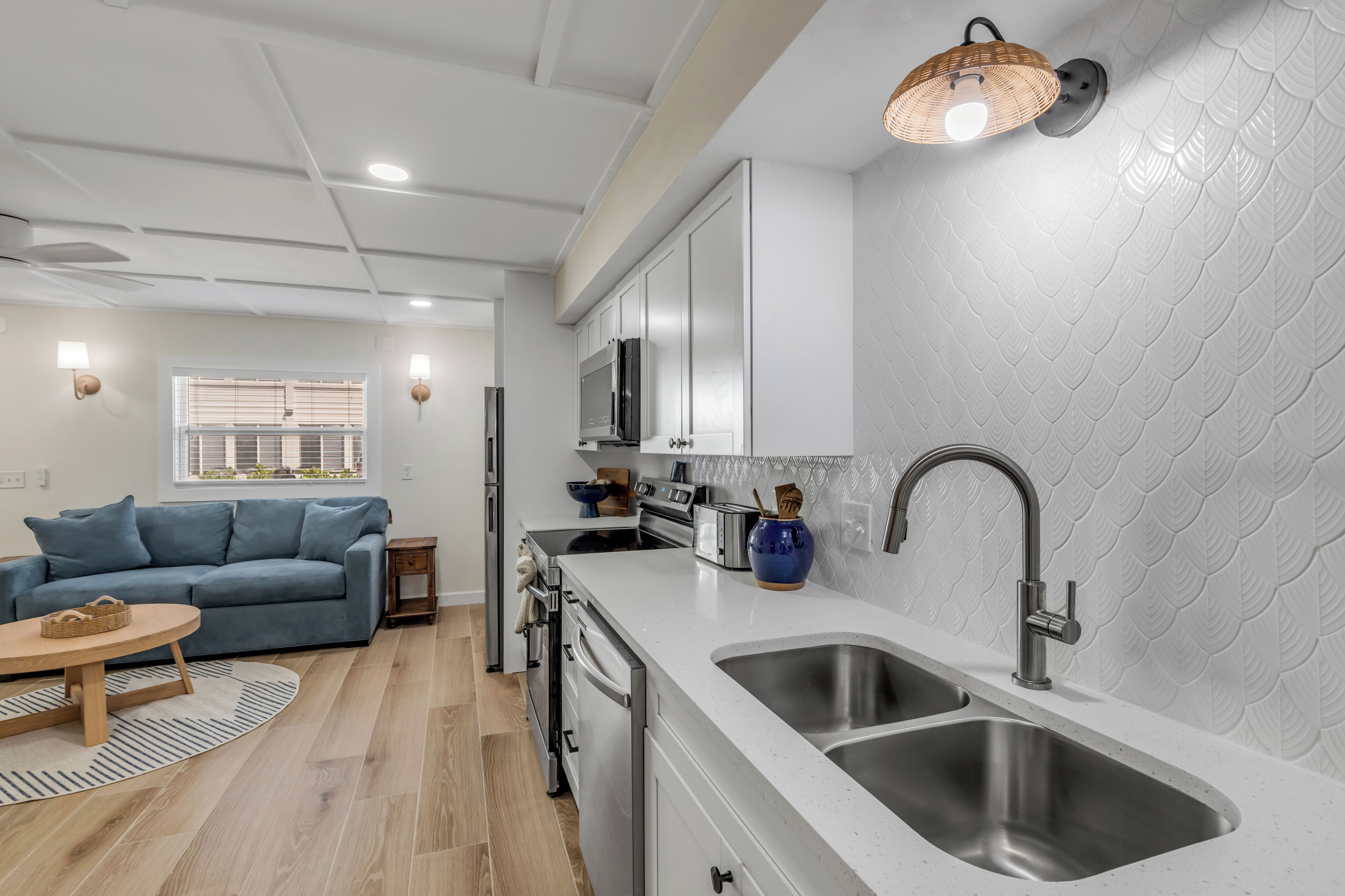 A modern kitchen with white cabinetry, stainless steel appliances, and a large sink.