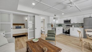A modern kitchen with white cabinets, a microwave, and a refrigerator. - Condo 12 Coastal Comfort (New Smyrna)