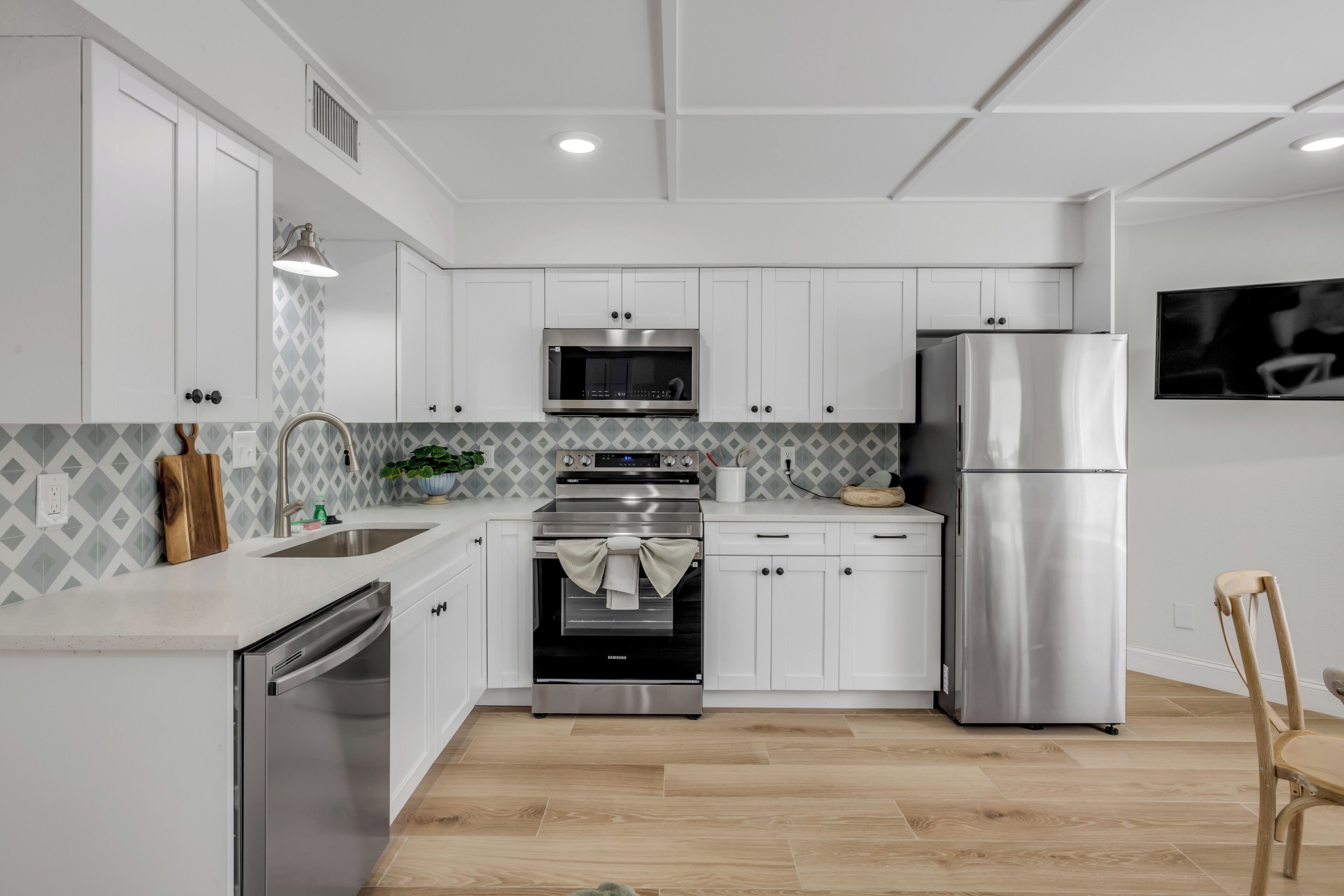 A modern kitchen with white cabinets, stainless steel appliances, a microwave, oven, and refrigerator.