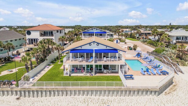 A beachfront hotel with a pool, lounge chairs, and a view of the ocean. - Condo 12 Coastal Comfort (New Smyrna)