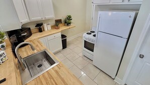 A kitchen with white cabinets, a stainless steel sink, a microwave, a stove, and a refrigerator. - LUXURY DOWNTOWN COLUMBUS TOWNHOME (Columbus)