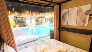 A hotel room with a bed, a window with a view of a pool, and a wall with artwork. - California Beach Pansol (Calamba)