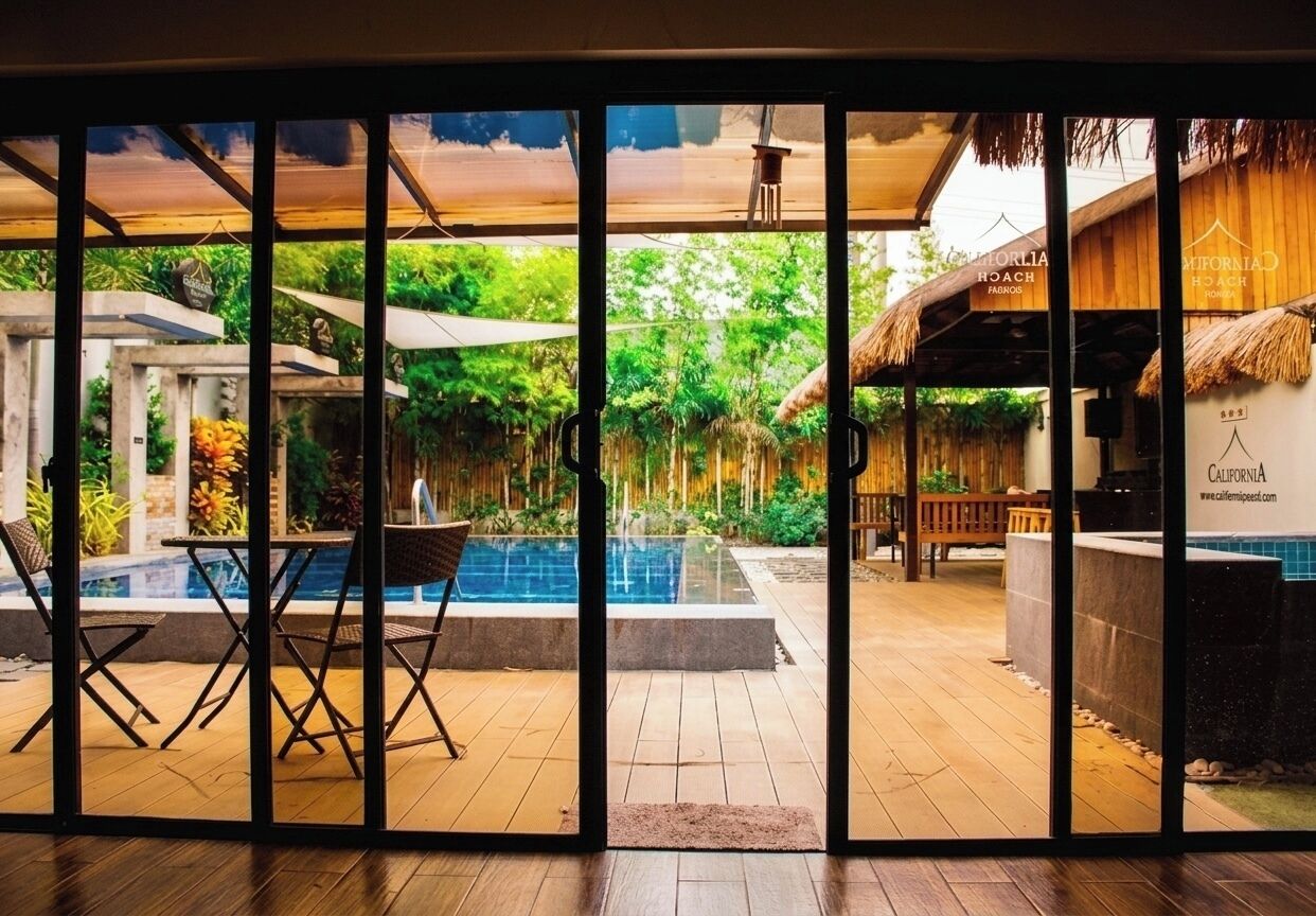 A pool area with a view of lush greenery, a bar, and outdoor seating.