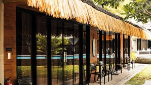A restaurant with a thatched roof, outdoor seating, and a view of a pool. - California Beach Pansol (Calamba)