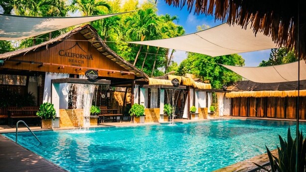 A pool area with a wooden structure labeled 'California Beach' and a thatched roof. - California Beach Pansol (Calamba)