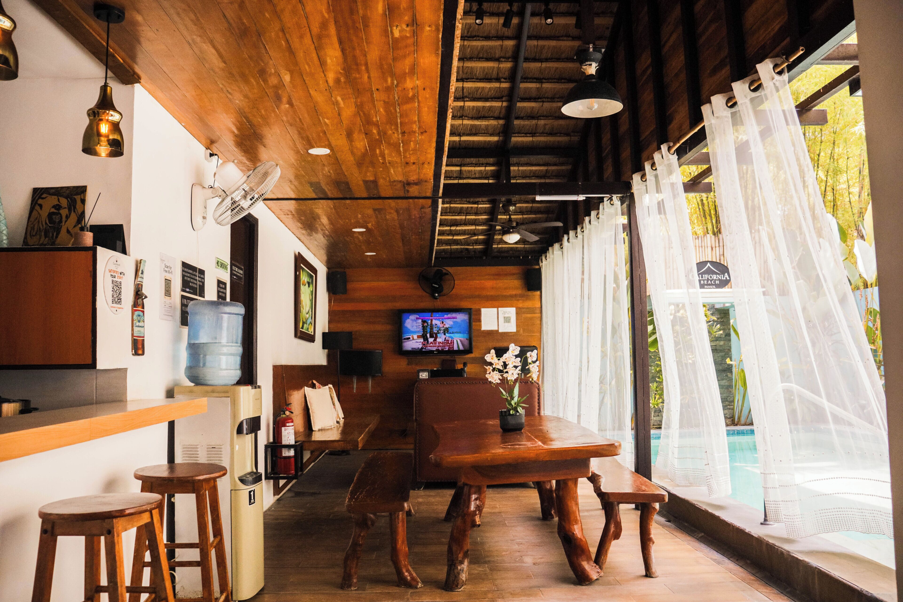 A wooden interior with a bar area, seating, and a TV.