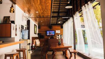 A wooden interior with a bar area, seating, and a TV.