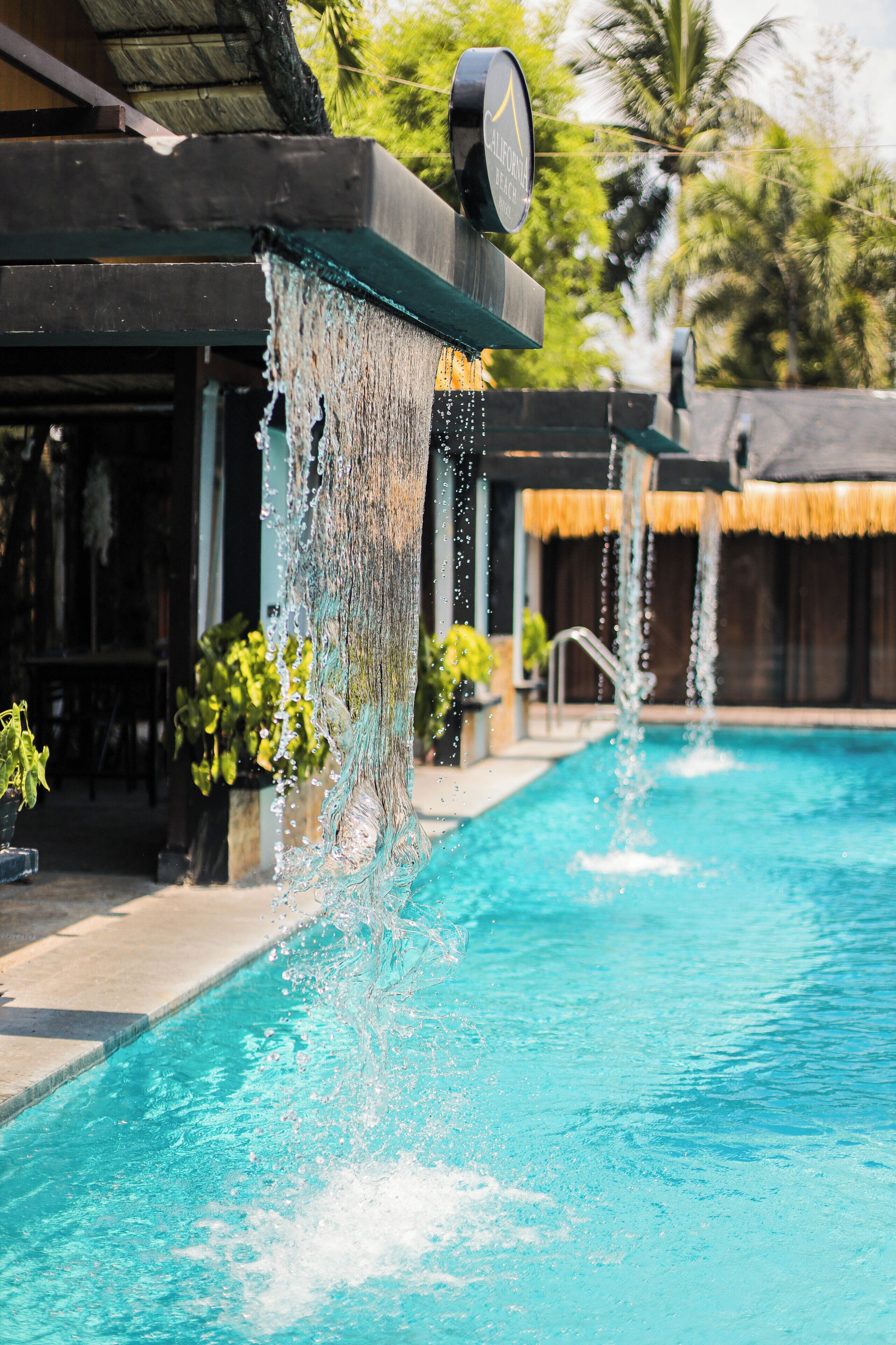 Piscina con elementos acuáticos, incluyendo una fuente y un reloj encima.