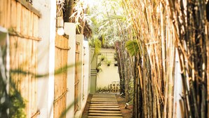 A narrow pathway flanked by bamboo and wooden fences, leading to a building entrance. - California Beach Pansol (Calamba)