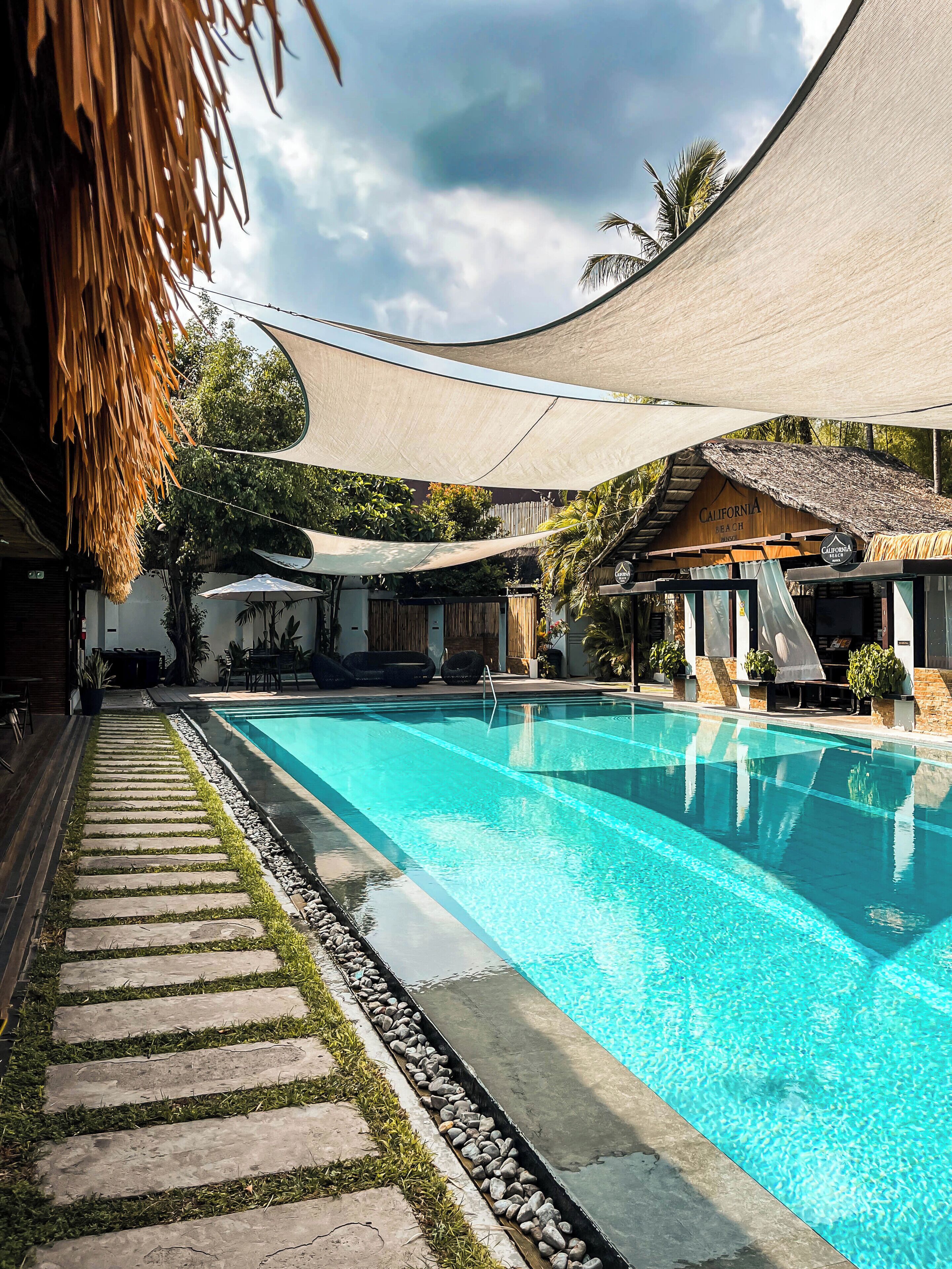 A swimming pool with a stone pathway, shaded by a canopy, and a building labeled 'California Beach.'