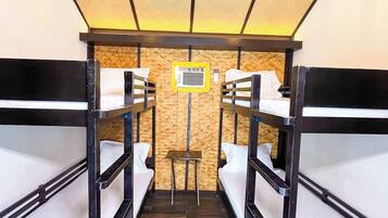 A bunk room with four beds, a small table, and two hanging lights.