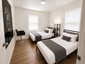 Ein Hotelzimmer mit zwei Betten, einem Schreibtisch, einem Stuhl und einem Bild an der Wand.