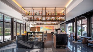 Uma área de bar moderna com uma vitrine de vidro, um quadro de cardápio e um espaço de estar com vista para o exterior.