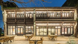 Um edifício tradicional com vários andares, grandes janelas e área de estar ao ar livre.