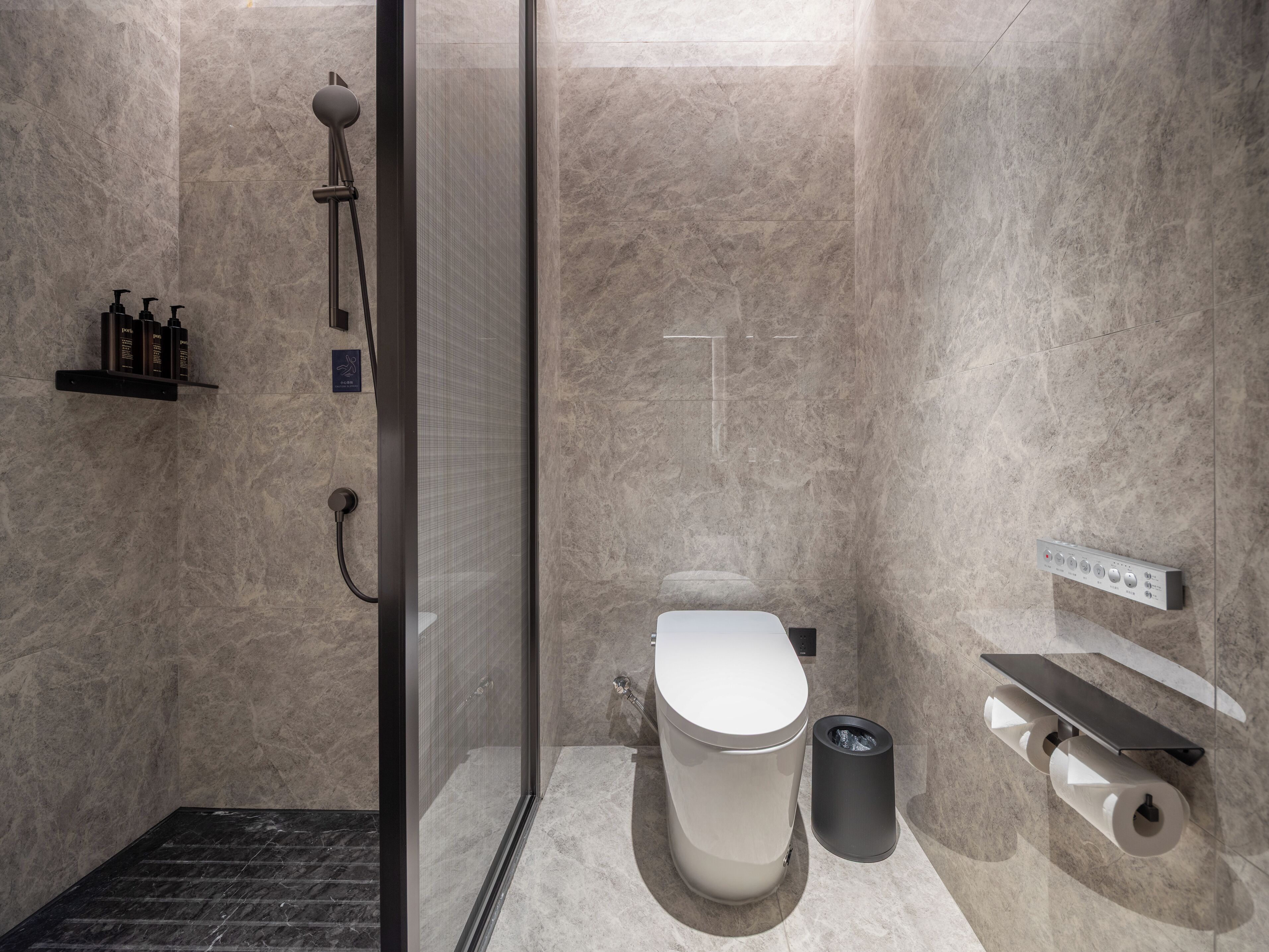Ein modernes Badezimmer mit einer gläsernen Duschkabine, Toilette, Bidet und Handtuchhalter.