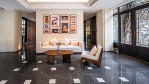 Um lobby moderno com um sofá branco, uma mesa de centro de madeira e quadros nas paredes.