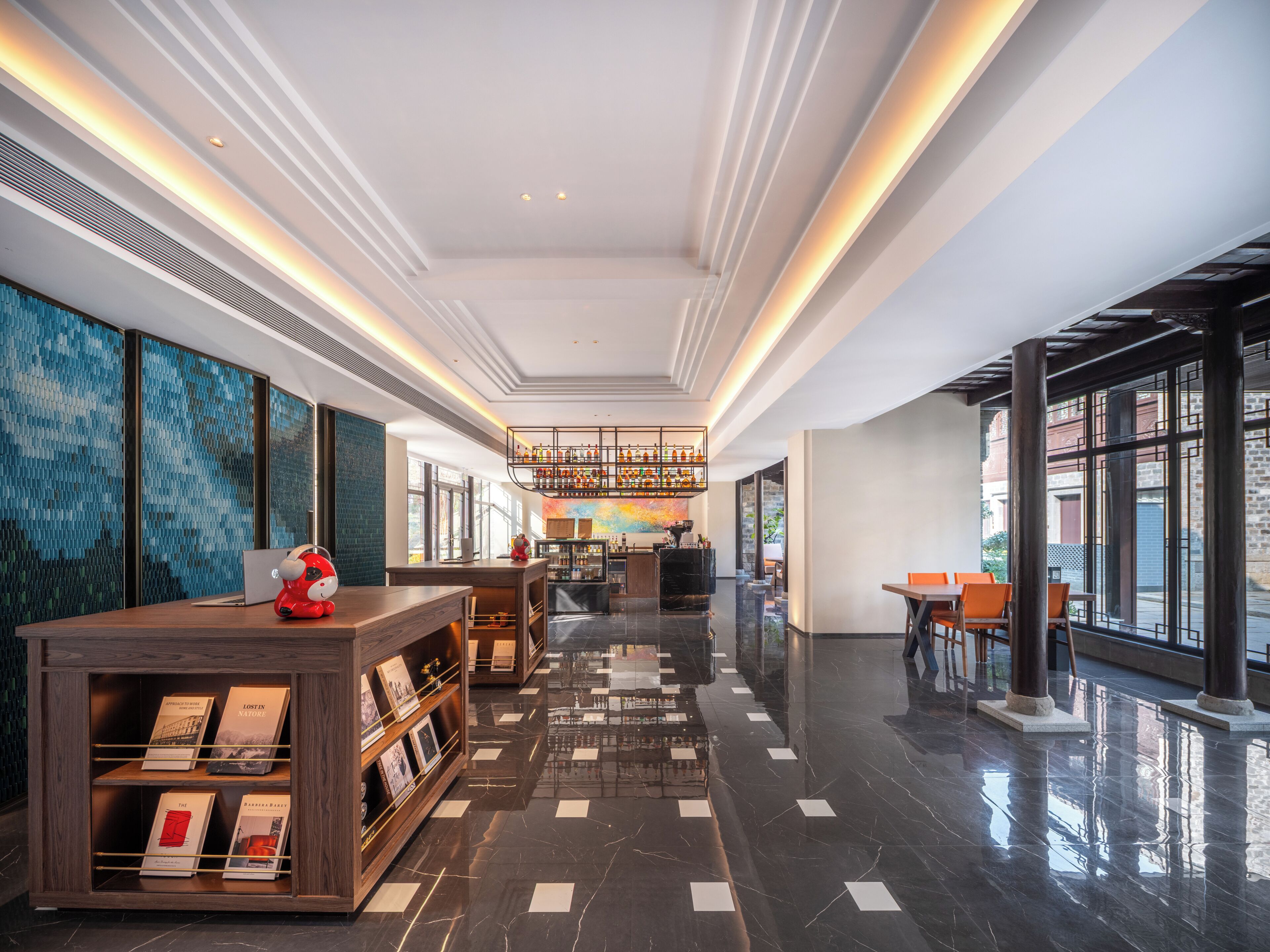 Un hall d’hôtel moderne doté d’un bar, de coins salon et d’une bibliothèque.